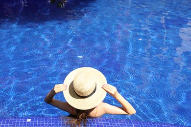 Photo of Girl with straw hat in swimming pool outdoors on sunny day, above view