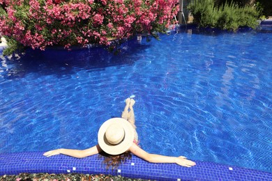 Photo of Girl with straw hat in swimming pool outdoors on sunny day, above view