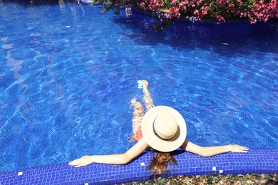 Photo of Girl with straw hat in swimming pool outdoors on sunny day, above view