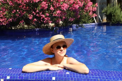 Photo of Girl with straw hat in swimming pool outdoors on sunny day