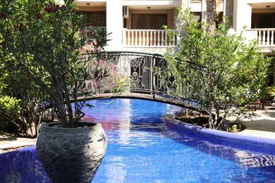 Photo of Outdoor swimming pool, bridge and green plants near hotel at luxury resort