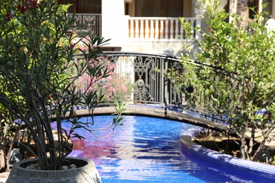 Photo of Outdoor swimming pool, bridge and green plants near hotel at luxury resort