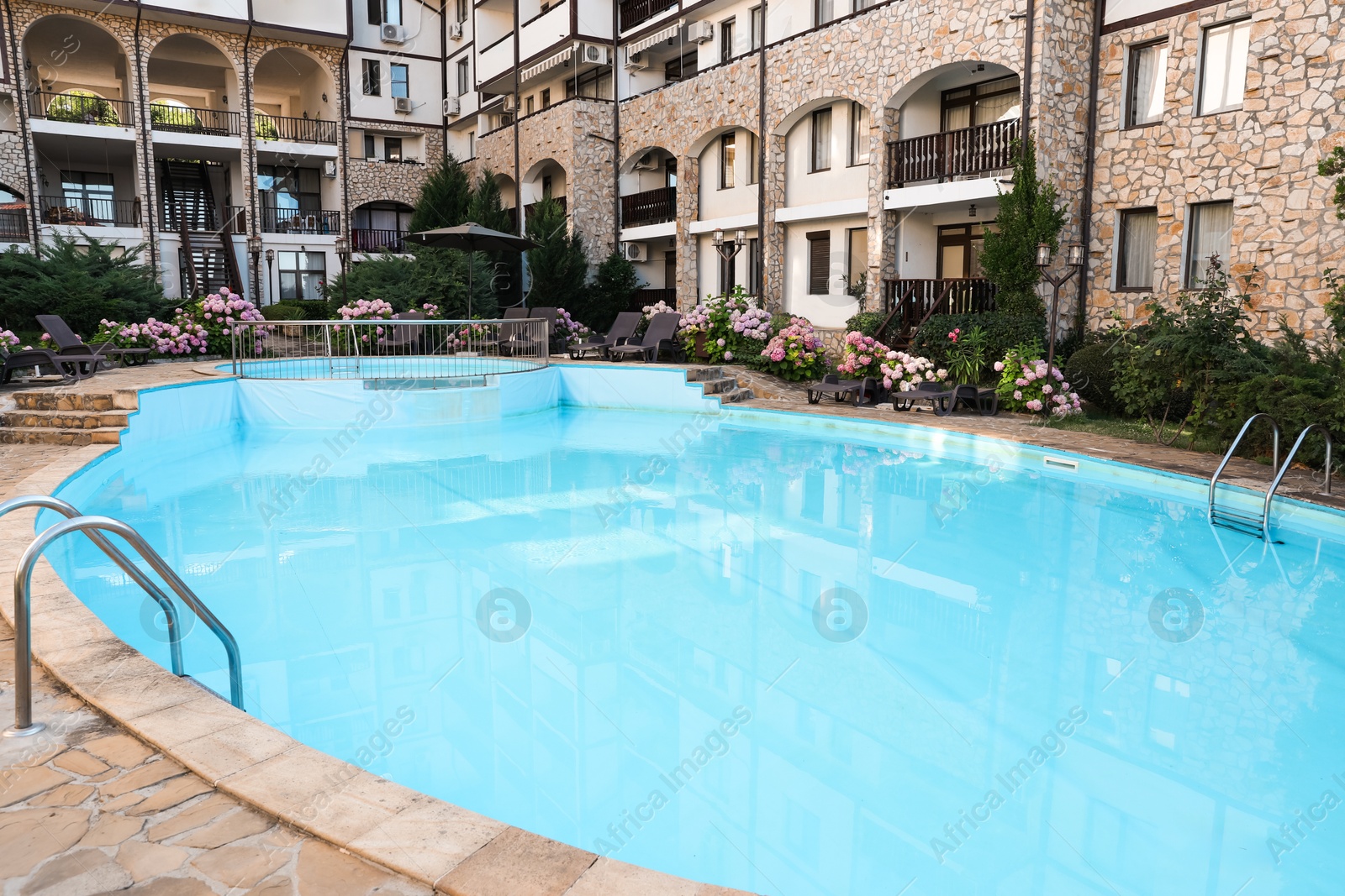 Photo of Outdoor swimming pool, sunbeds and beautiful hydrangea flowers near hotel at luxury resort