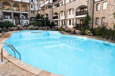 Photo of Outdoor swimming pool, sunbeds and beautiful hydrangea flowers near hotel at luxury resort