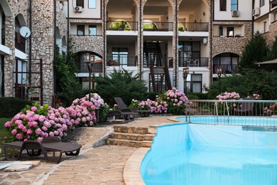Photo of Outdoor swimming pool, sunbeds and beautiful hydrangea flowers near hotel at luxury resort