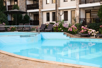 Photo of Outdoor swimming pool, sunbeds and beautiful hydrangea flowers near hotel at luxury resort