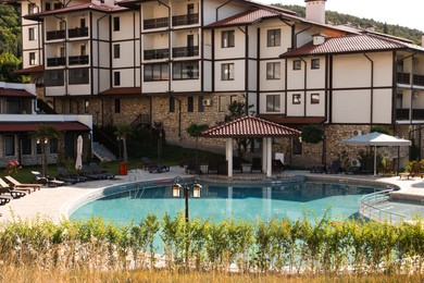 Photo of Outdoor swimming pool and sunbeds near hotel at luxury resort