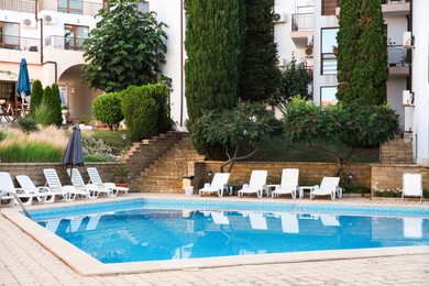 Photo of Outdoor swimming pool and sunbeds near hotel at luxury resort