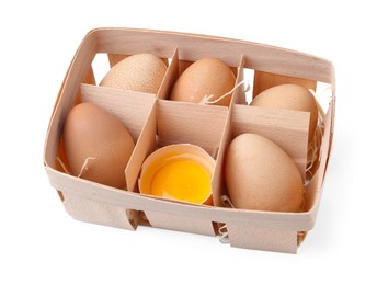 Photo of Whole and broken chicken eggs in wooden tray isolated on white