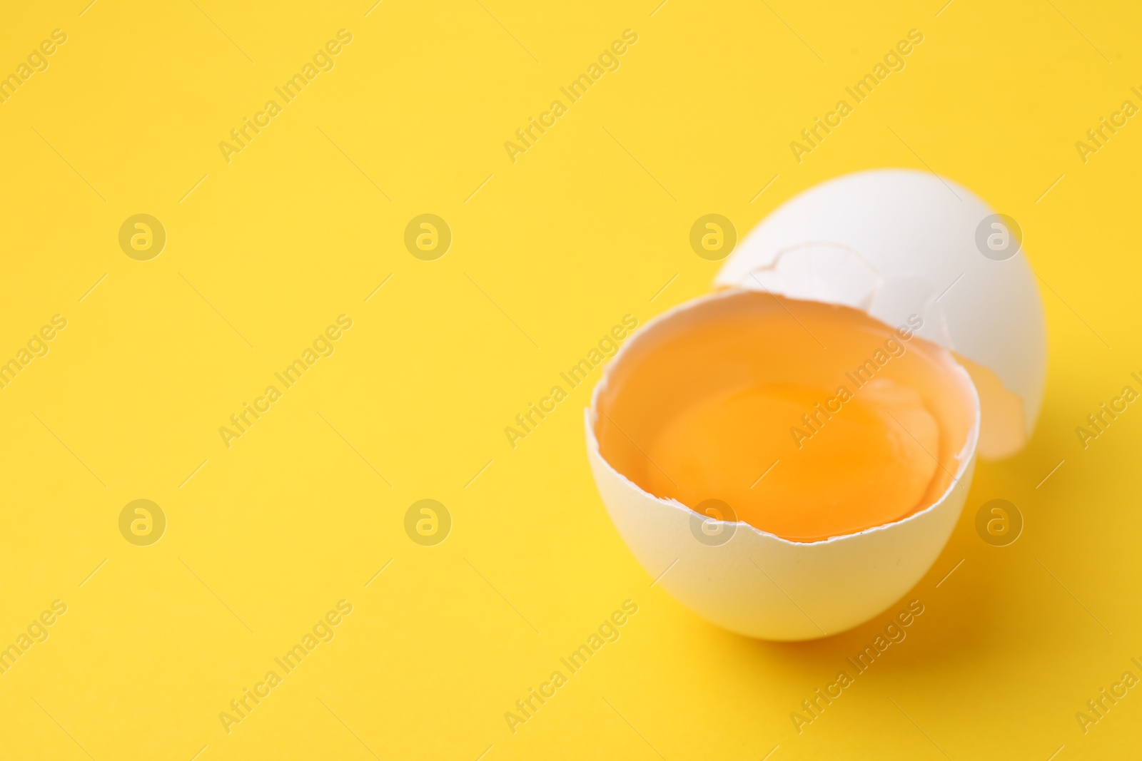 One broken chicken egg on yellow background, closeup. Space for text Photo of One broken chicken egg on yellow background, closeup. Space for text