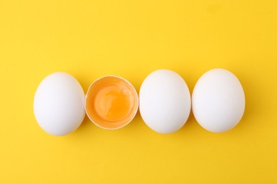 Photo of Whole and broken chicken eggs on yellow background, top view