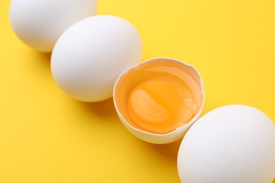 Photo of Whole and broken chicken eggs on yellow background, closeup
