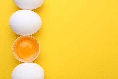 Photo of Whole and broken chicken eggs on yellow background, top view. Space for text