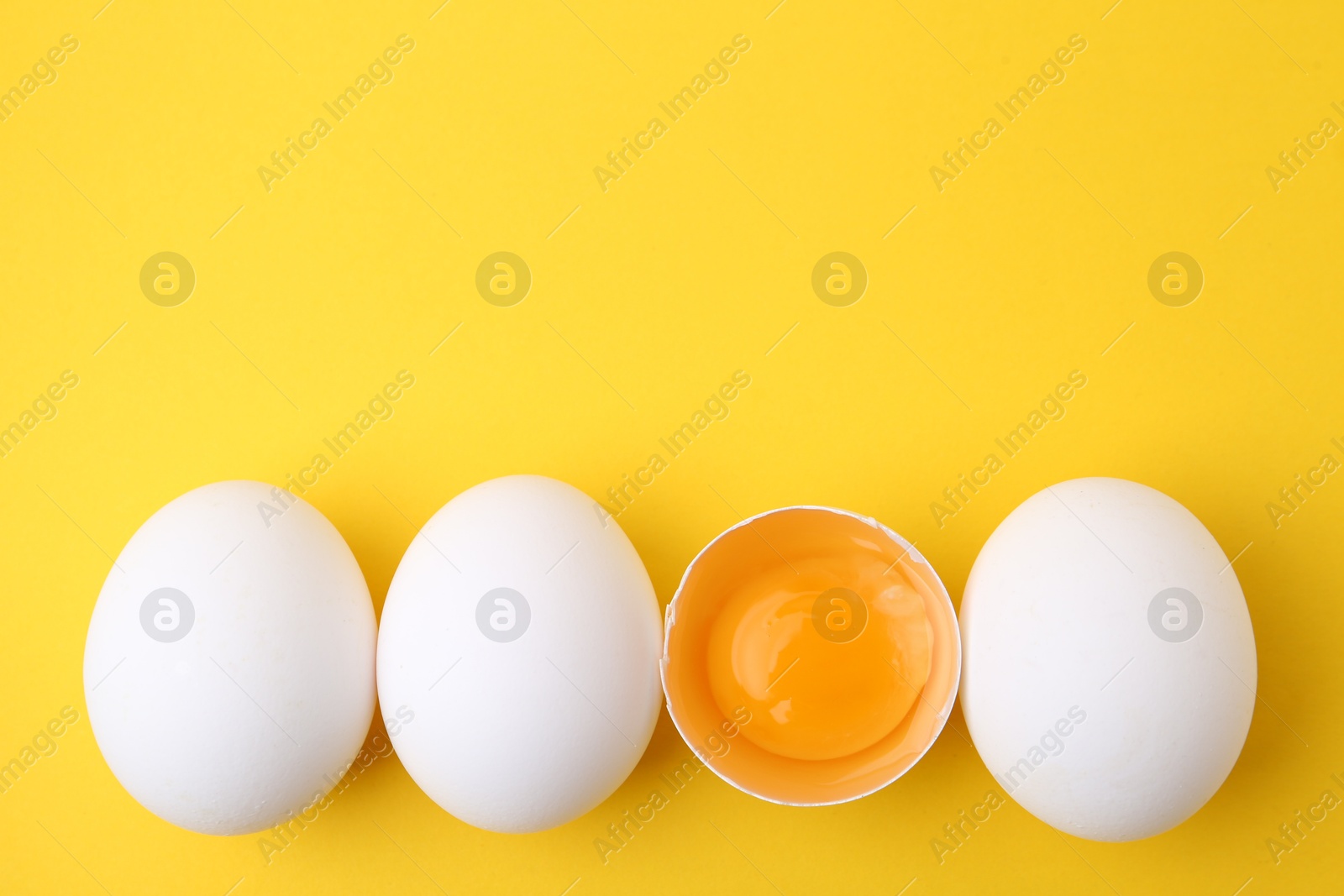 Whole and broken chicken eggs on yellow background, top view. Space for text Photo of Whole and broken chicken eggs on yellow background, top view. Space for text