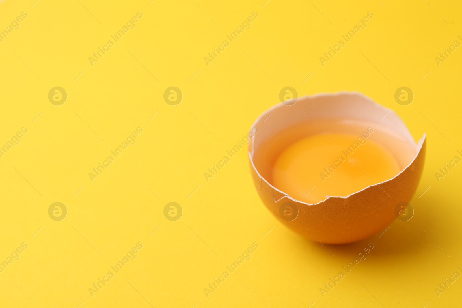 One broken chicken egg on yellow background, closeup. Space for text Photo of One broken chicken egg on yellow background, closeup. Space for text