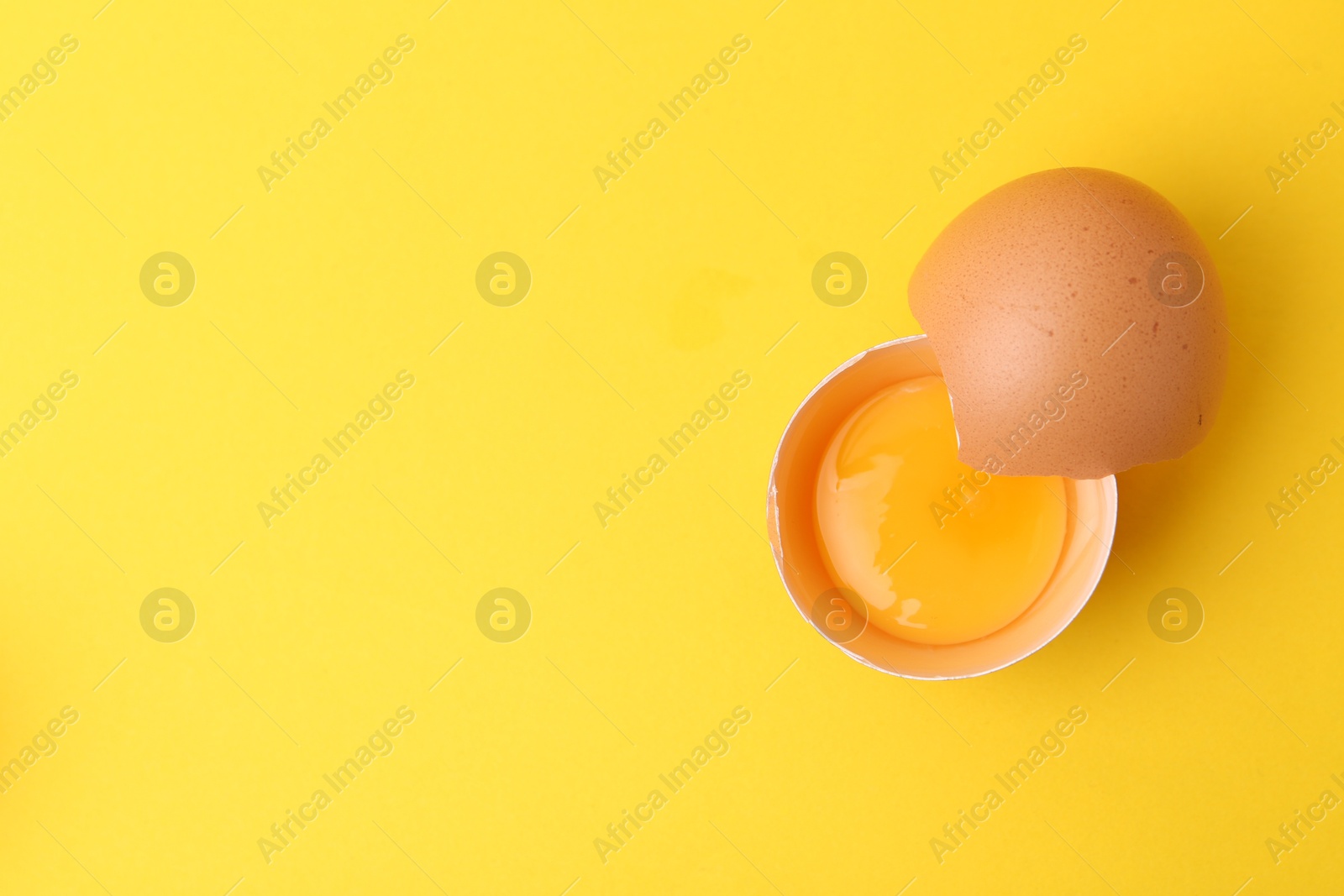 One broken chicken egg on yellow background, top view. Space for text Photo of One broken chicken egg on yellow background, top view. Space for text