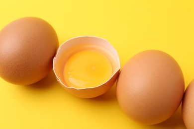 Photo of Whole and broken chicken eggs on yellow background, closeup