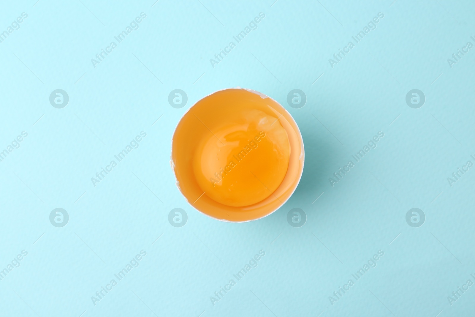 One broken chicken egg on light blue background, top view Photo of One broken chicken egg on light blue background, top view