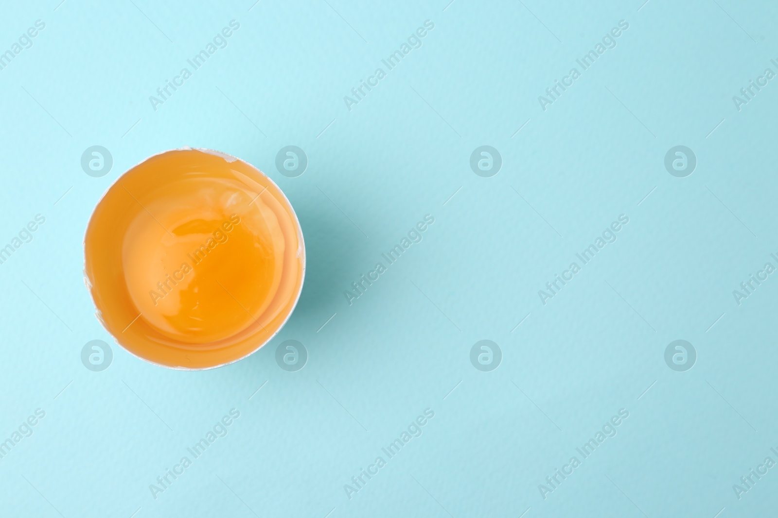 One broken chicken egg on light blue background, top view. Space for text Photo of One broken chicken egg on light blue background, top view. Space for text