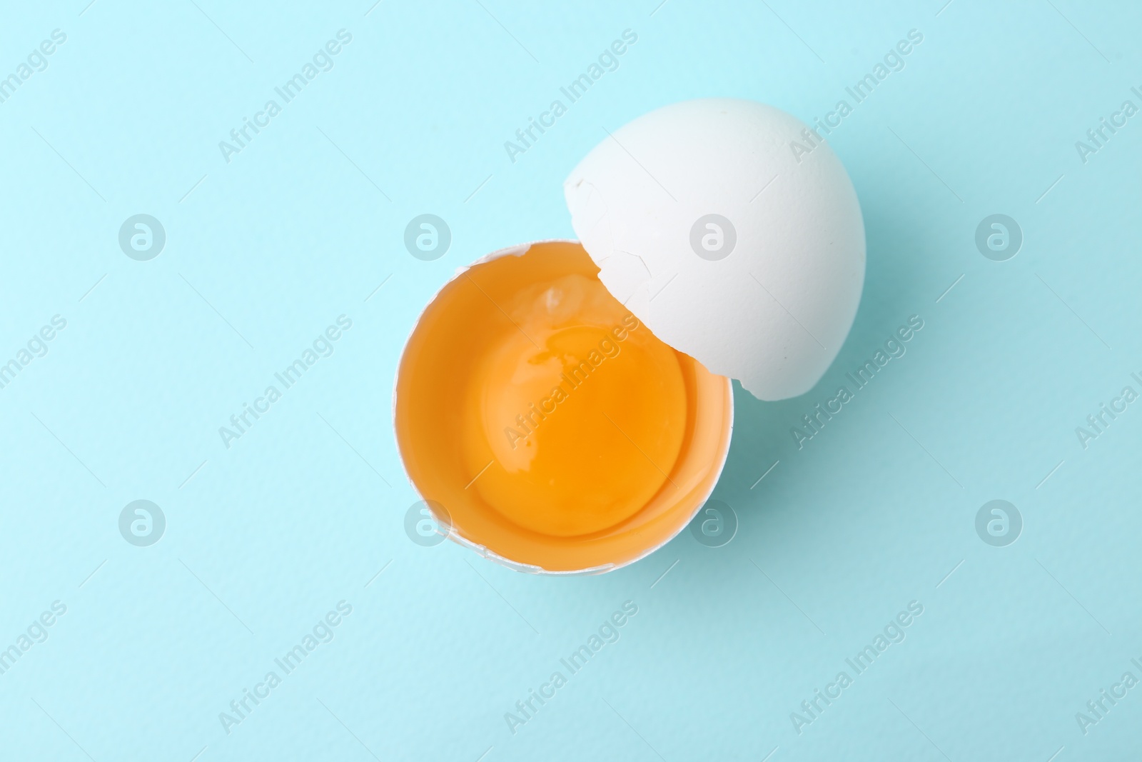 One broken chicken egg on light blue background, top view Photo of One broken chicken egg on light blue background, top view