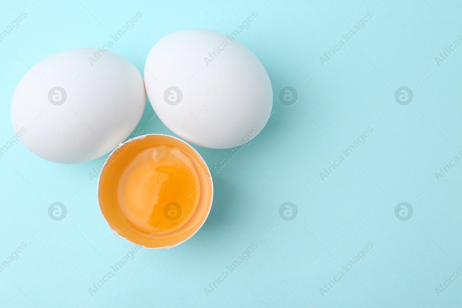 Whole and broken chicken eggs on light blue background, top view. Space for text Photo of Whole and broken chicken eggs on light blue background, top view. Space for text