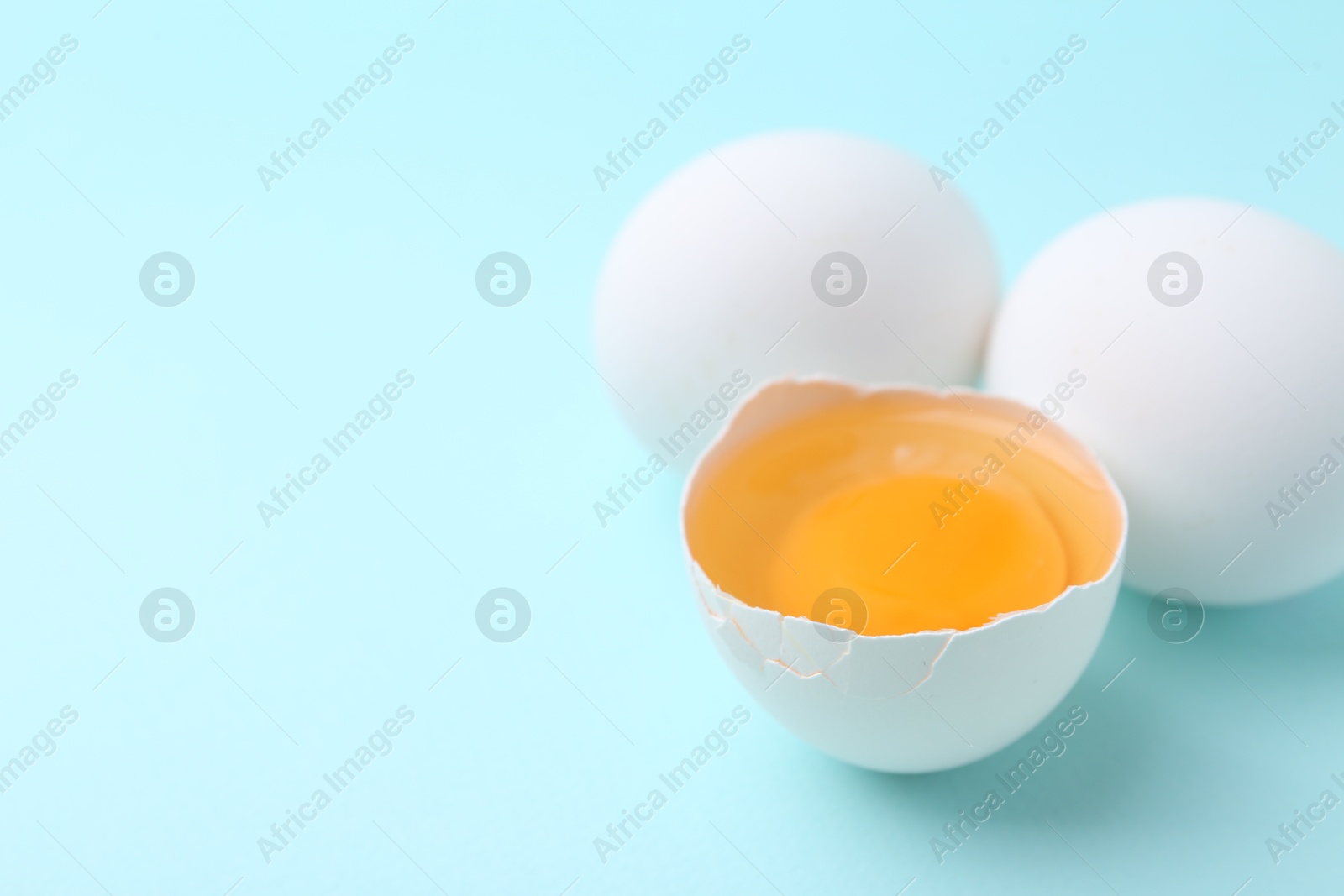 Whole and broken chicken eggs on light blue background, closeup. Space for text Photo of Whole and broken chicken eggs on light blue background, closeup. Space for text