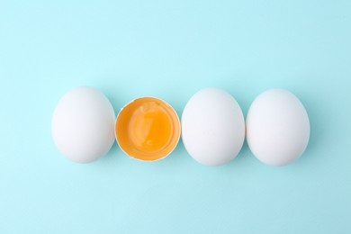 Photo of Whole and broken chicken eggs on light blue background, top view