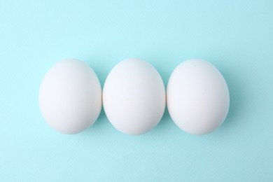 Photo of Raw chicken eggs on light blue background, top view
