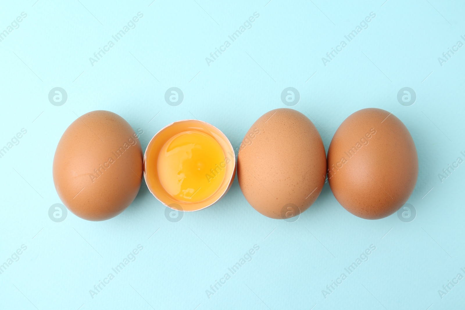 Whole and broken chicken eggs on light blue background, top view Photo of Whole and broken chicken eggs on light blue background, top view