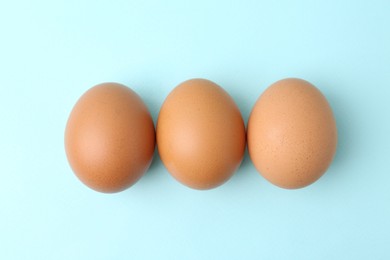 Photo of Raw chicken eggs on light blue background, top view