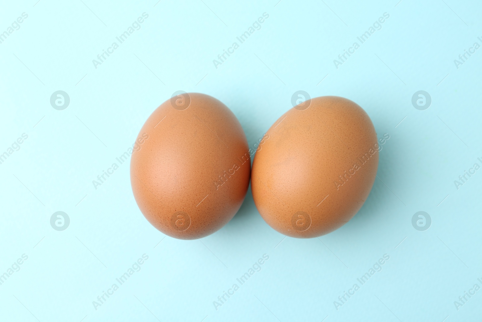 Raw chicken eggs on light blue background, top view Photo of Raw chicken eggs on light blue background, top view