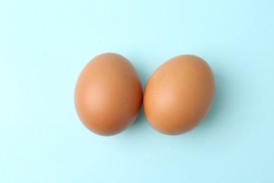 Photo of Raw chicken eggs on light blue background, top view