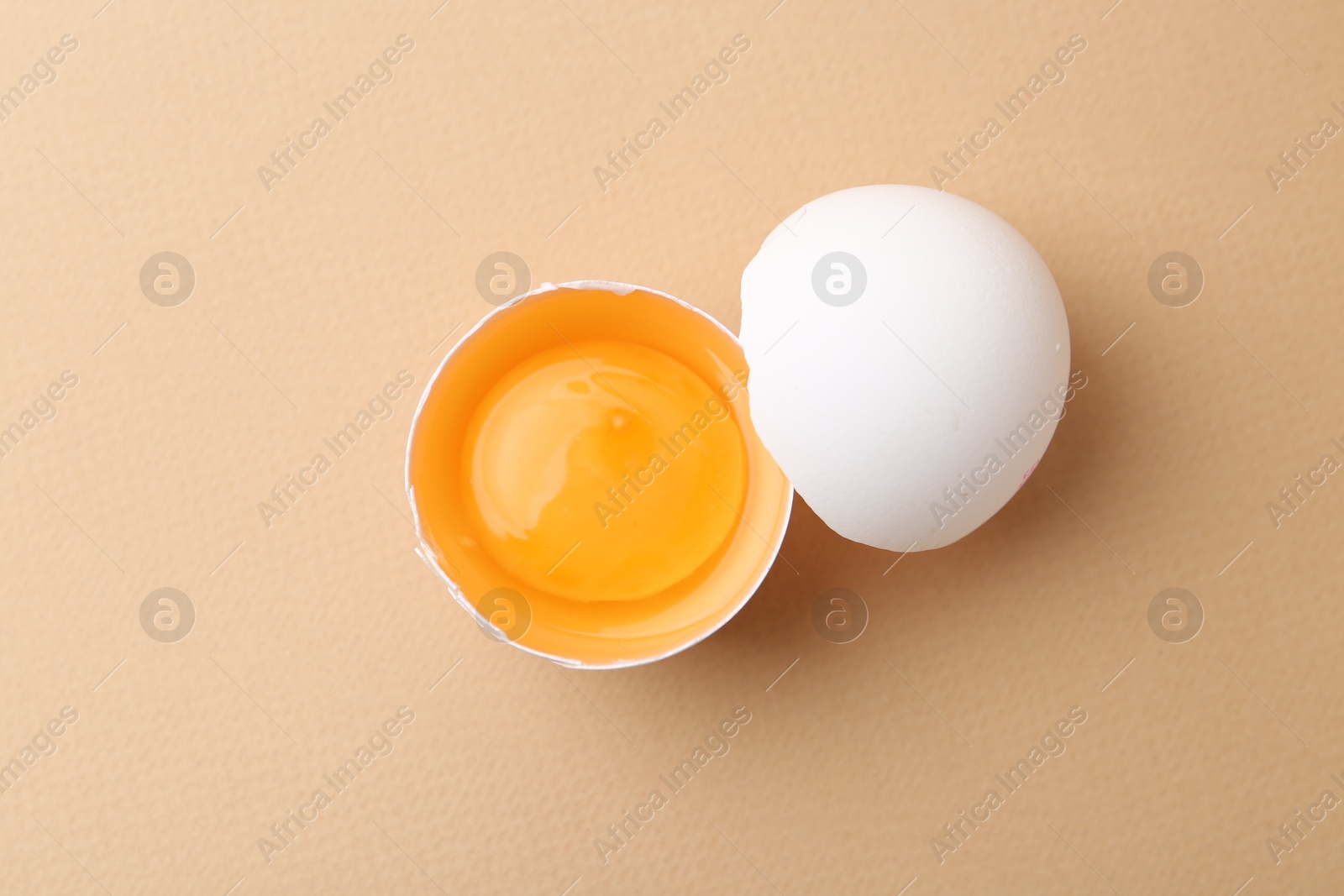 One broken chicken egg on beige background, top view Photo of One broken chicken egg on beige background, top view