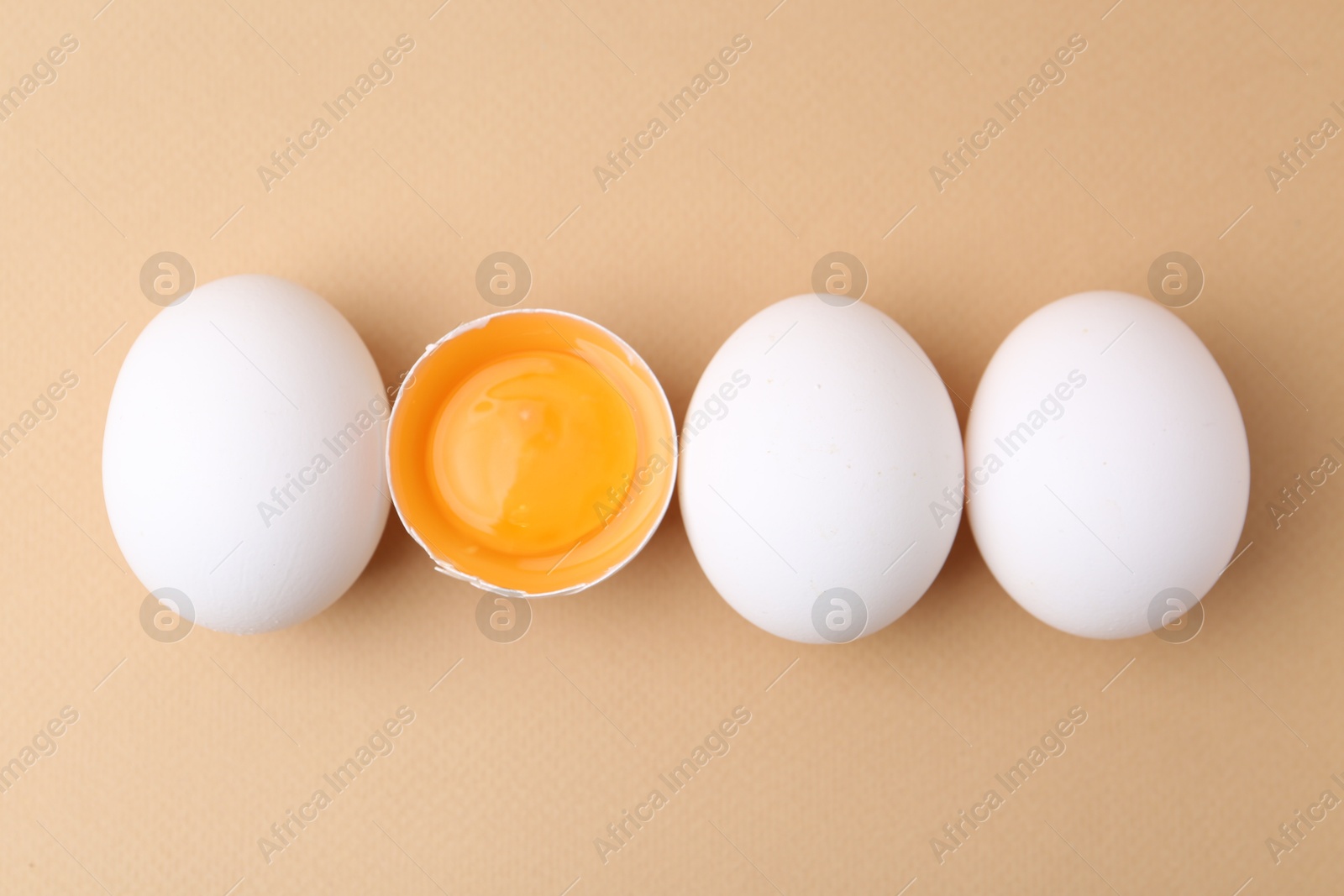 Whole and broken chicken eggs on beige background, top view Photo of Whole and broken chicken eggs on beige background, top view