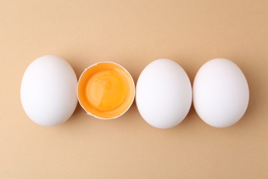 Photo of Whole and broken chicken eggs on beige background, top view
