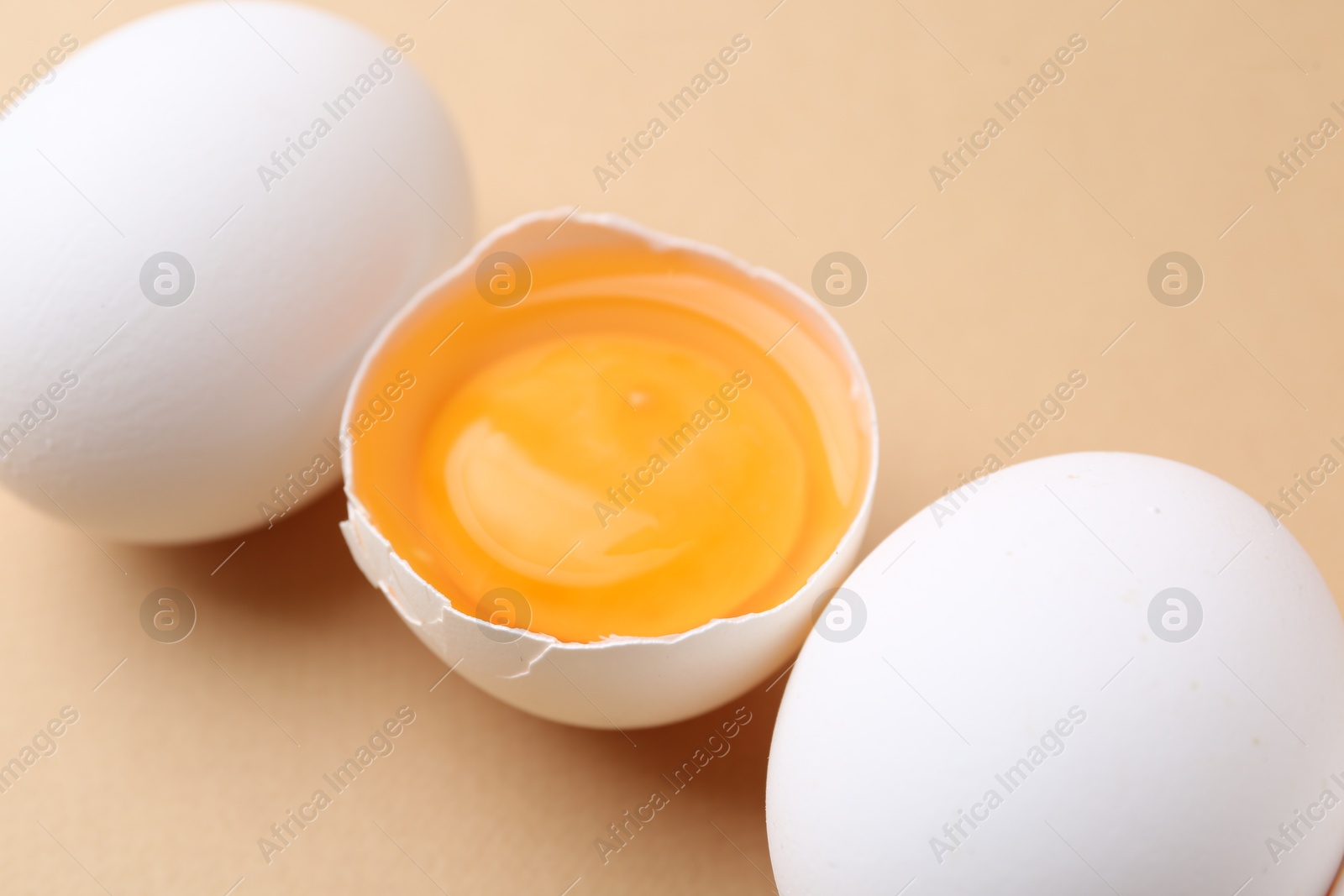 Whole and broken chicken eggs on beige background, closeup Photo of Whole and broken chicken eggs on beige background, closeup