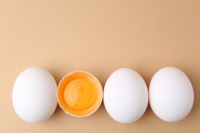 Photo of Whole and broken chicken eggs on beige background, top view. Space for text