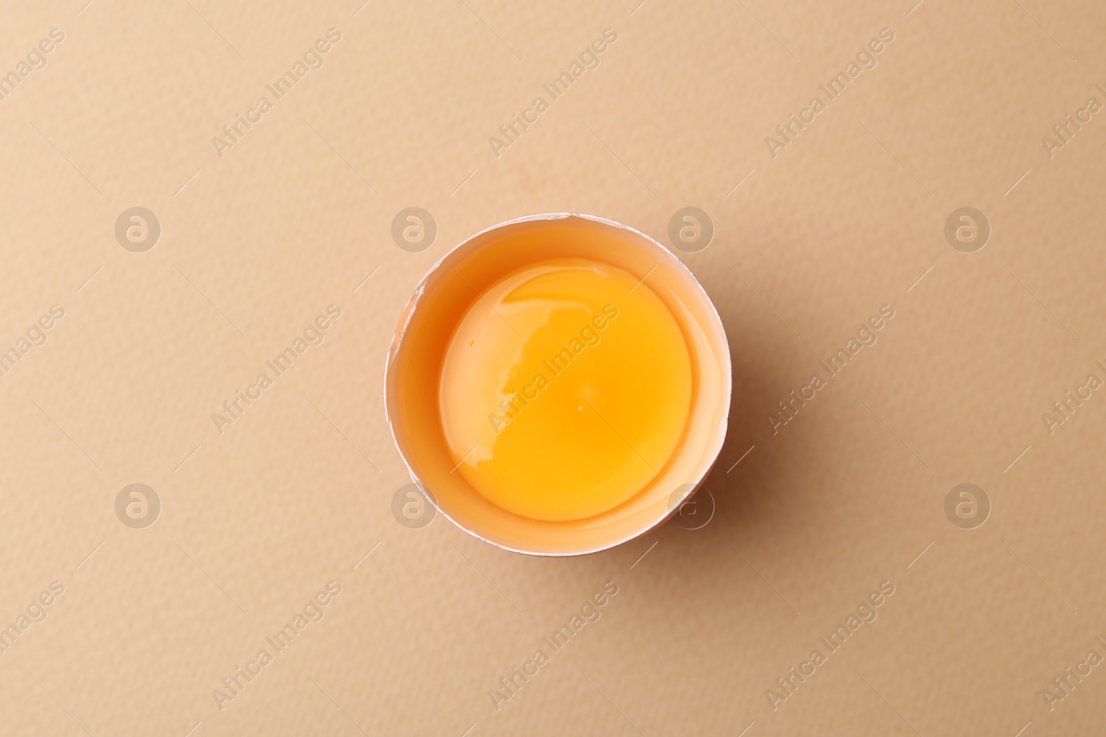 One broken chicken egg on beige background, top view Photo of One broken chicken egg on beige background, top view