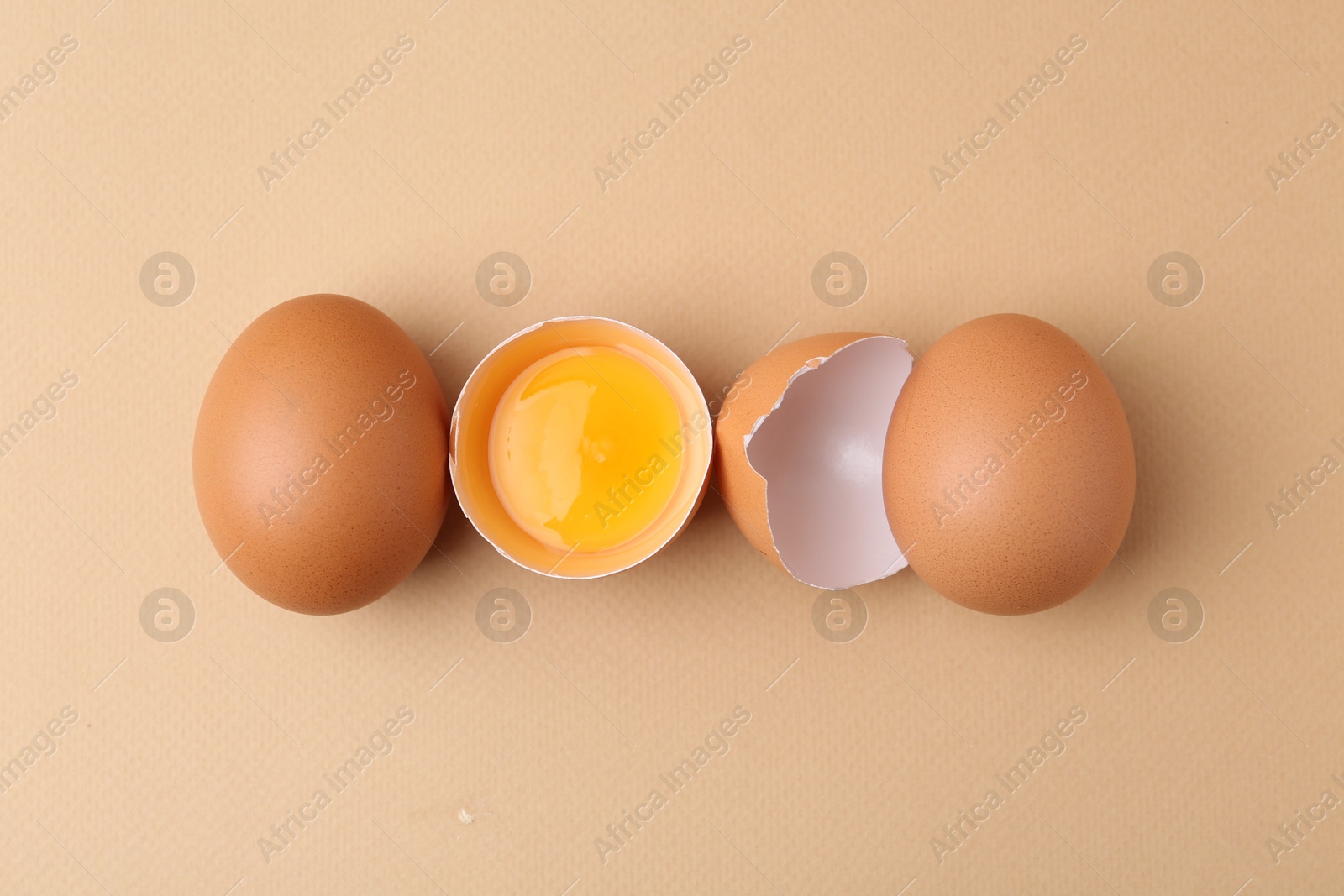 Whole and broken chicken eggs on beige background, top view Photo of Whole and broken chicken eggs on beige background, top view