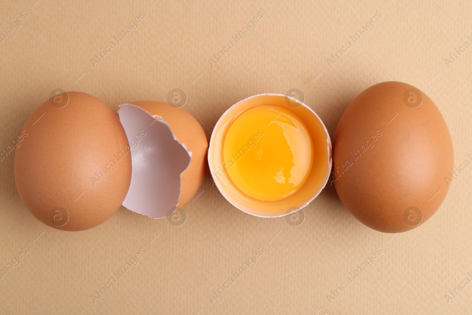 Whole and broken chicken eggs on beige background, top view Photo of Whole and broken chicken eggs on beige background, top view