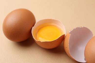 Photo of Whole and broken chicken eggs on beige background, closeup