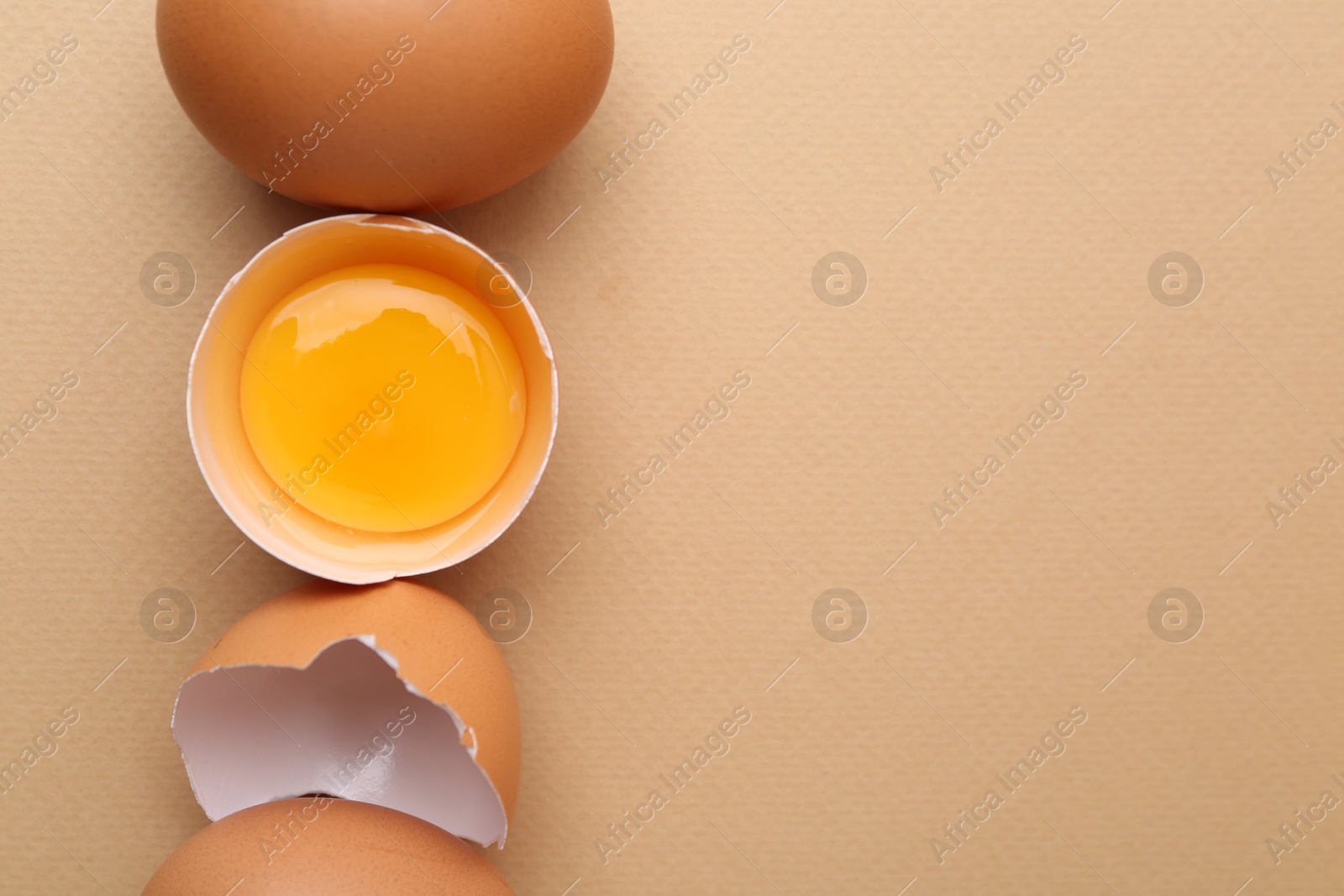 Whole and broken chicken eggs on beige background, top view. Space for text Photo of Whole and broken chicken eggs on beige background, top view. Space for text