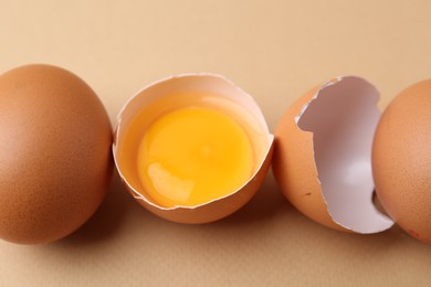 Photo of Whole and broken chicken eggs on beige background, closeup