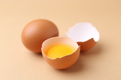 Photo of Whole and broken chicken eggs on beige background, closeup