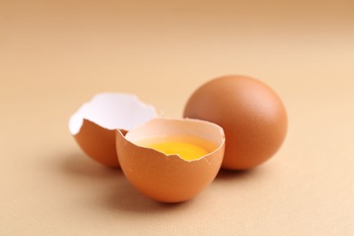 Photo of Whole and broken chicken eggs on beige background, closeup