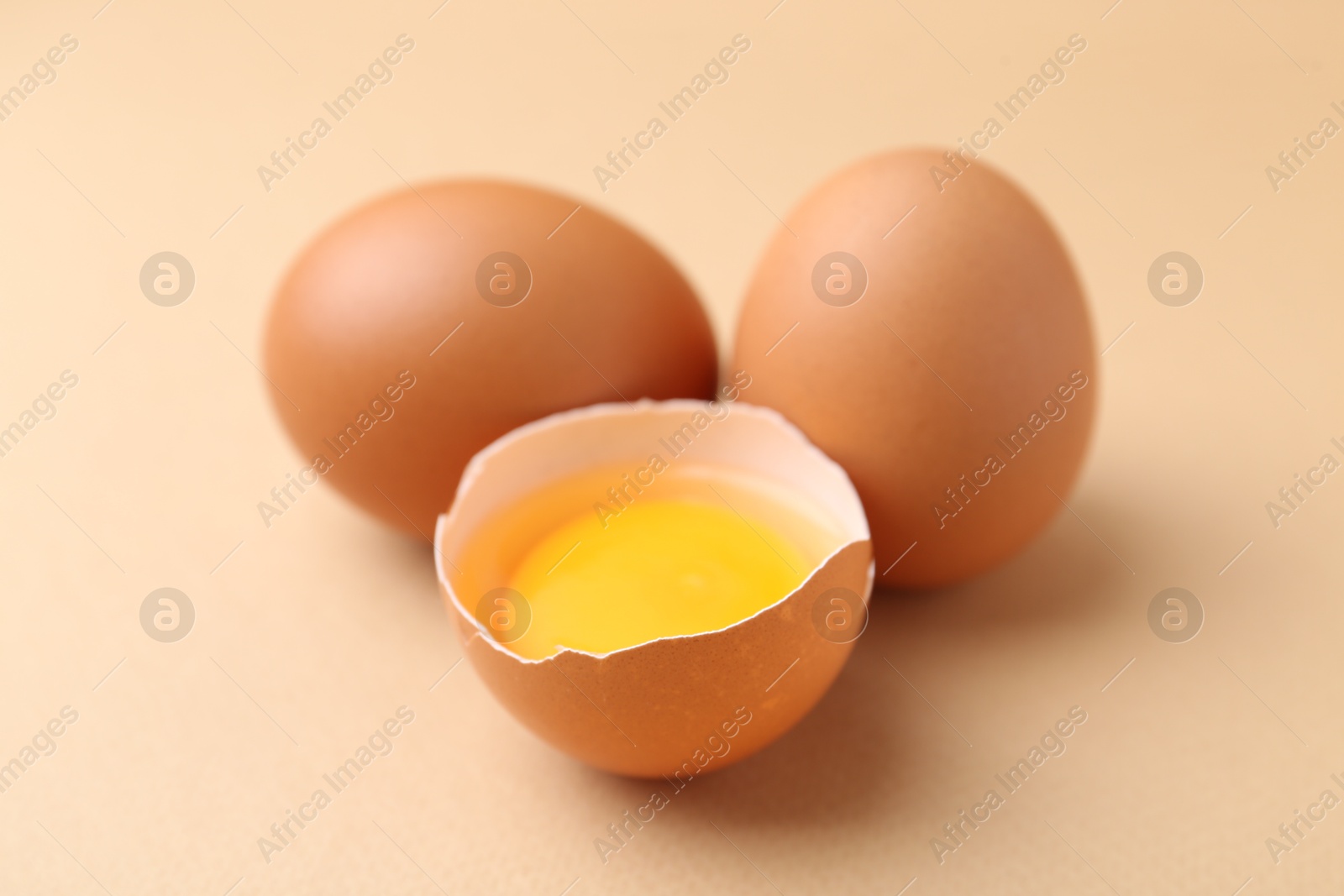 Whole and broken chicken eggs on beige background, closeup Photo of Whole and broken chicken eggs on beige background, closeup