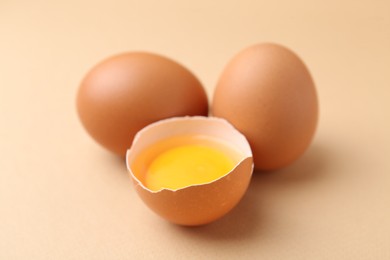 Photo of Whole and broken chicken eggs on beige background, closeup