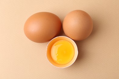 Photo of Whole and broken chicken eggs on beige background, top view