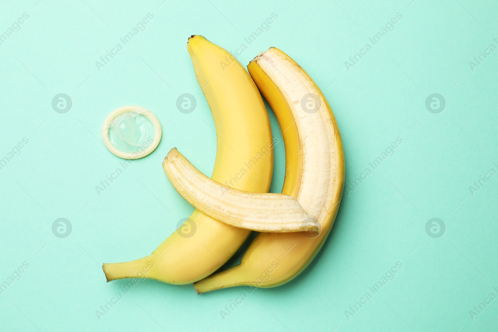 Sex education. Bananas and condom on turquoise background, flat lay Photo of Sex education. Bananas and condom on turquoise background, flat lay