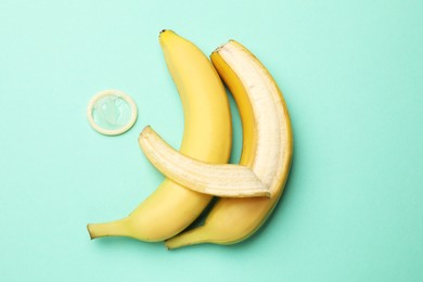 Photo of Sex education. Bananas and condom on turquoise background, flat lay